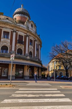 MAKO, HUNGARY - 17 Mart. 2024: Mako 'nun merkezindeki eski bir binanın önündeki geçitte genç bir kadın