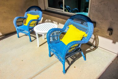 Two Blue Wicker Arm Chairs And Table On Front Porch
