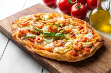 Tahta arka planda domatesli, peynirli ve deniz mahsullü pizza.