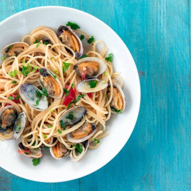 Plate of delicious Italian spaghetti topped with clams, viewed from above and in square format