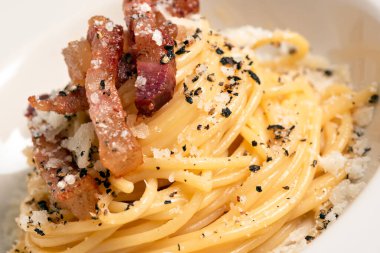 Lezzetli bukatini alla carbonara tabağı. Yumurtalı İtalyan makarnası, guanciale ve pecorino tarifi.