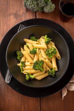 Tahta zemin üzerinde izole edilmiş brokolili lezzetli bir makarna tabağı, vejetaryen İtalyan yemeği.