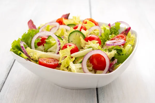 Beyaz arka planda domatesli sağlıklı sebze salatası.