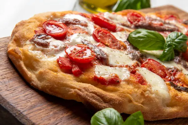 Delicious typical roman pizza with tomato, mozzarella and anchovies, italian food