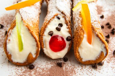Lezzetli Sicilyalı cannoli 'ye yakın, ricotta kreması, çikolata parçacıkları ve şekerli meyvelerle dolu geleneksel bir İtalyan tatlısıdır.