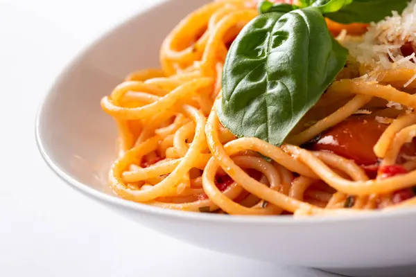 stock image spaghetti with tomato sauce, cheese and basil leaves on a white background.