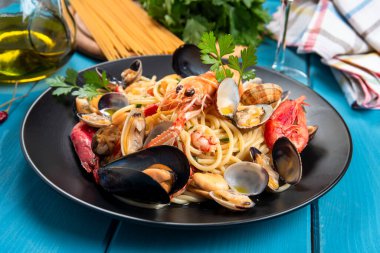 Spaghetti allo scoglio ve siyah tabakta deniz ürünleri.