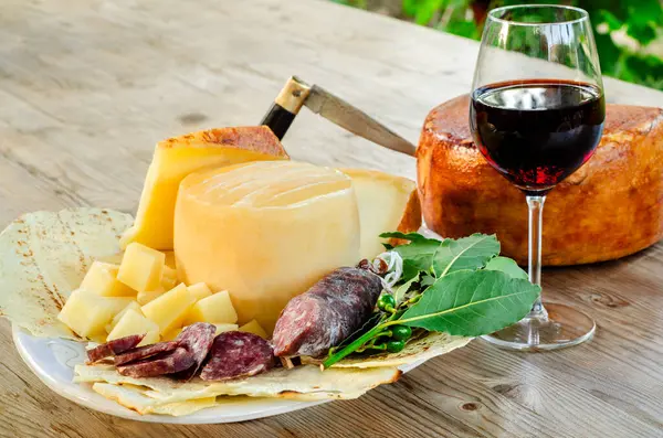 Stock image italian antipasto with cheese and sausage, red wine glass in the restaurant