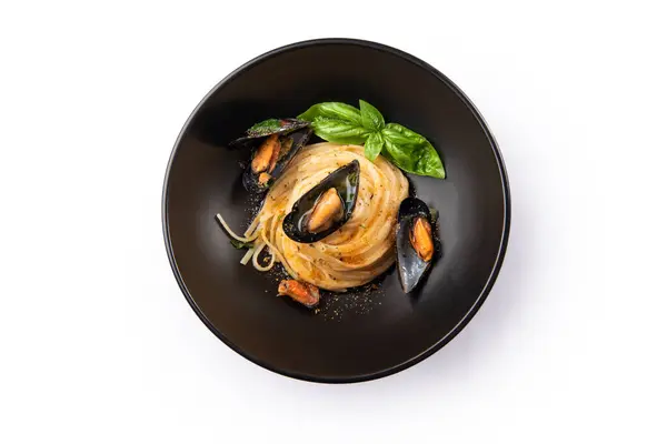 stock image close-up view of delicious pasta with seafood in black plate on white background 