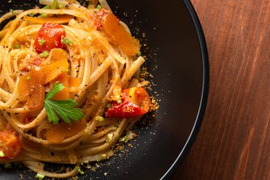 Lezzetli İtalyan makarnasının yakın plan görüntüsü. Ahşap masa üzerinde siyah tabakta deniz ürünleri var.