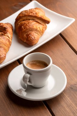 Tahta masada iki kruvasan ve kahve fincanı.