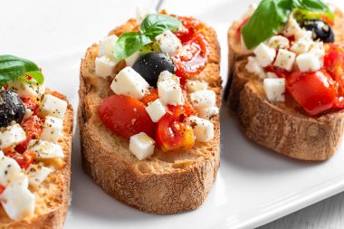 Domatesli bruschetta, mozzarella ve fesleğen yapraklı.
