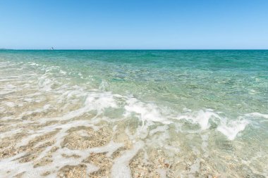Güneşli yaz gününde turkuaz deniz suyuyla kumlu sahil. 