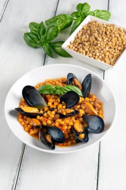 Beyaz kasede midye ve fregola makarna.