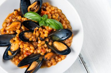 Taze fesleğenle süslenmiş midye ve kuskus.