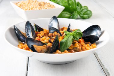 Taze fesleğenle süslenmiş midye ve fasulye.