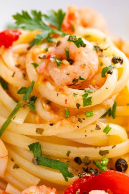 Maydanoz ve domatesle süslenmiş karidesli makarna.