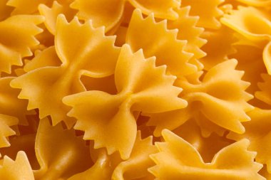 Yakından bakınca, pişmemiş sarı papyonlu makarna parçaları görünüyor.