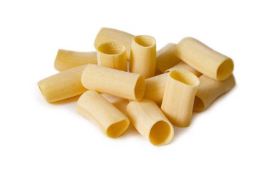 Pişmemiş rigatoni makarna parçaları beyaz arka plana saçılmış.