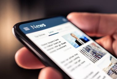 Telefonda haberler var. İnternet sitesinden gazete okuyor. Dijital yayın ve dergi modeli. Dijital web portalındaki son manşetlerle basın desteği. Akıllı telefondan medya sitesini izleyen okuyucu.