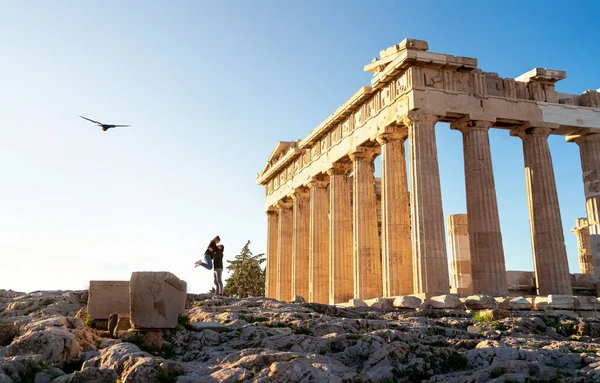 Yunanistan, Atina. Akropolis 'teki turist çift. Parthenon harabelerinde iki kişi. Seyahat ve turizm. Kadın ve erkek romantik bir buluşma, şehir tatili ya da balayı. Günbatımında antik tapınak manzarası.