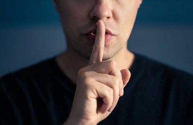 Sır ve sessizlik. Sessiz sessiz jest, parmaklar dudaklarda. Elle ağıza ifade veren bir adam. Tabu konusu, sansür, özgürlük ya da konuşma özgürlüğü. Komplo teorisi. Gizli konuşma..