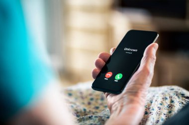 Yaşlı bir kadın ve telefon numarası gizli. Kıdemli olgun bayan, dolandırıcı ve dolandırıcı. Aşk ve aşk aldatmacası. Akıllı telefonu elinde tutarak. Yayın balığı ya da dolandırıcı. Phishing kavramı.