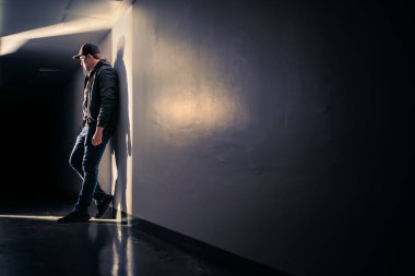 Karanlık koridorda dikilen ciddi üzgün adam. Sahne ışıkları altında gizemli bir adam. Dramatik ışık ve gölge. Sapık ya da serseri. Bekleyen, saklanan, gizlice dinleyen biri. Umutsuzluk, travma veya keder.