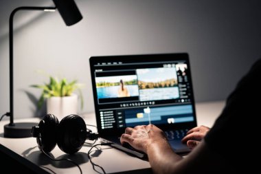 Film editörüyle video düzenleme. Bilgisayarla film yapmak. Kulaklık ve dizüstü bilgisayar. Ses, ses ve müzik tasarımcısı. İçerik üretim yazılımıyla çalışan bir adam. Yaratıcı multimedya stüdyosu. Görsel efekt