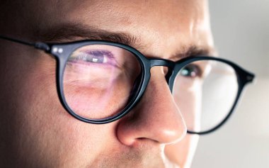 Gözlükler ve gözler. Ekrana bakıyorum. İşine odaklan. Bilgisayar, dizüstü bilgisayar, telefon ya da televizyon yansıması. Yorgun, şaşı gözler. Görme ve görme bozukluğu olan ciddi bir adam. Zeki inek çocuk. Yüzdeki ışığı izle.