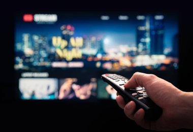 Televizyonda film akışı servisimizi izliyoruz. Talep abonelik hizmeti ve televizyondaki platform üzerine video. İnternette yayınlanan diziler, filmler ve gösteriler. Uzaktan kumanda kullanan adam. Kişi tarama modeli VOD.