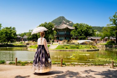 Seul, Güney Kore. Hanbok kadın giyiyordu. Gyeongbokgung Sarayı Bahçesi. Kore giysi geleneği. Arka planda Hyangwonjeong Pavyonu var. Gyeongbok 'ta bir turist. Geleneksel kültür turu ve seyahat.