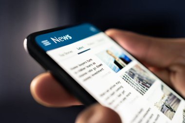 İnternette haberler. Gazete manşetleriyle telefon et ve besle. Dijital basın makalesi. Okuyucu son başlıkları izliyor. Akıllı telefondan sahte medya yayın sitesi. Mobil ekranda metin okuyan adam.