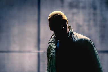 Karanlık sokaktaki şüpheli suçlu ve yabancı adam. Gölgelerde saklanan sapık. Bir hırsızın silueti ve gizli yüzü. Gangster kötü adam. İsimsiz kimlik. Suç şüphelisi. Grunge arkaplanı