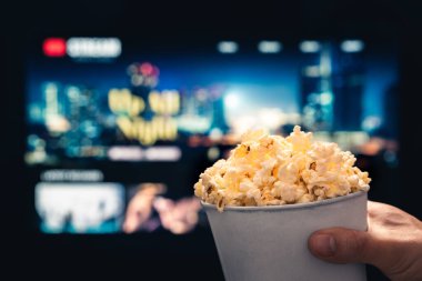 Televizyon yayını ve patlamış mısır. Televizyondaki akış servisinden film izliyordum. Film gecesi ve atıştırmalık. Patlamış mısır, kanepe ve vod serisi. Oturma odasında ev sineması. İstenilen video içeriği çevrimiçi.