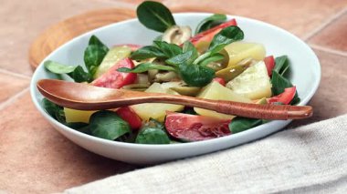 Beyaz tabakta sebze salatası, patates, domates ve zeytin. Yakın plan.