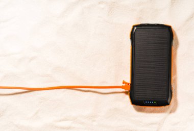 Kumun üzerinde uzanan güneş paneli ile taşınabilir enerji bankası yolculuk sırasında güneş enerjisi biriktirir. Alternatif eko enerji üretimi.