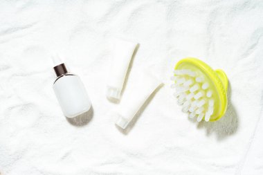 Doğal deniz kozmetik ve mineral konseptine dayalı spa tedavileri. Beyaz bir kumdaki sahte kozmetik şişeleri ve masaj fırçasıyla yapılmış. Üst görünüm.