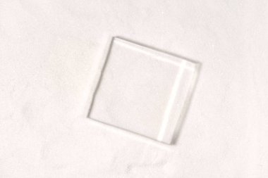 Kozmetik ürün sunumu veya paket reklamı için cam kaidesi. Üst Manzara. Kumun üzerindeki kare camlı maket sahnesi. Reklam için sahne. Boşluğu kopyala.