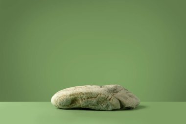Yeşil arka planda taş olan bir maket sahnesi. Kozmetik ürün sunumu ya da paket reklamı için doğal kaide. Reklam için sahne. Boşluğu kopyala.