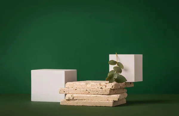 stock image Product presentation mockup scene made with travertine tiles, white cubes and eucalyptus branch on a green background. Front view, copy space.