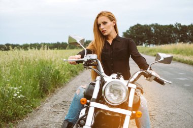 Güzel kızıl saçlı bayan, motosikletli, motosikletli. Tonu ayarlanmış resim.