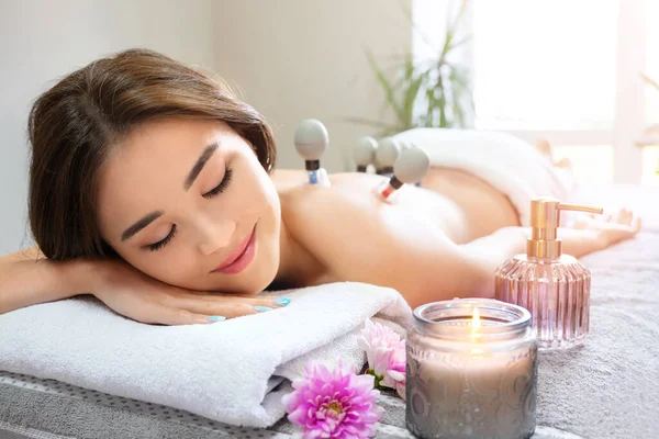 Cupping vacuum massage treatment for beautiful asian woman. Cupping massage enhances lymphatic drainage and blood flow to the tissues and eliminates fatigue and back pain. Cozy massage room atmosphere.