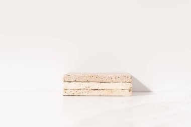 Mockup product presentation podium made with travertine tiles on white background. Front view.