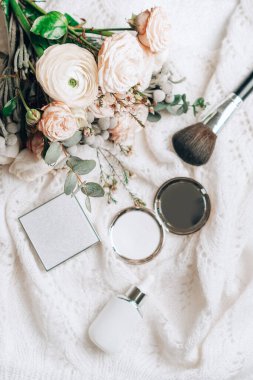 Ranunculus ve kozmetik aksesuarlı şık bir buketle yatıyordu. Dikey fotoğrafçılık.