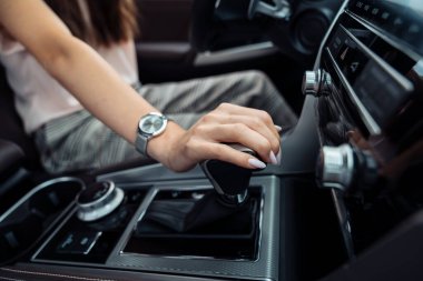 Direksiyonda bir kadın var. Modern bir arabada vites seçen genç bir kadının eli. Otomatik vites değiştirme.