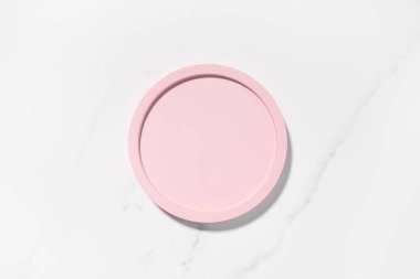 Güzellik kozmetik ürünleri sunumu düz yerde, beyaz mermer masa üzerinde pembe yuvarlak şekilli, fotokopi alanı olan bir sahne. Moda güneş ışığı, üst manzara. Stüdyo fotoğrafçılık.
