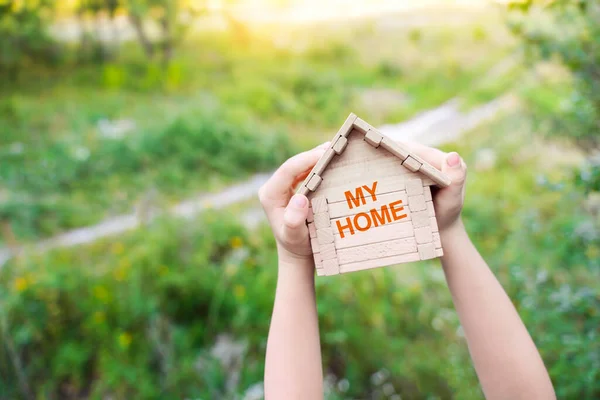 My home background. House construction, home for the family. Concept with kid\'s hands holding little wooden house with text My home.
