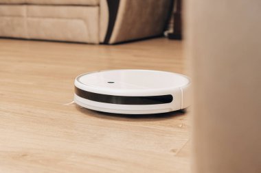 Robot elektrikli süpürge oturma odasındaki ahşap zeminde çalışıyor. Modern akıllı ev, akıllı ev temizleme asistanı.