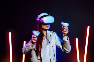 VR kulaklıkla, neon ışıklarla sanal gerçeklik oyunu oynayan bir kız. joystickli gözlüklü kadın oyuncu.